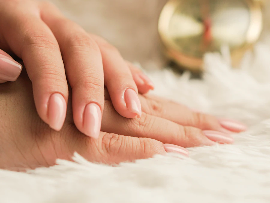 Twee handen met verzorgde, lichtroze nagels op een zachte witte deken