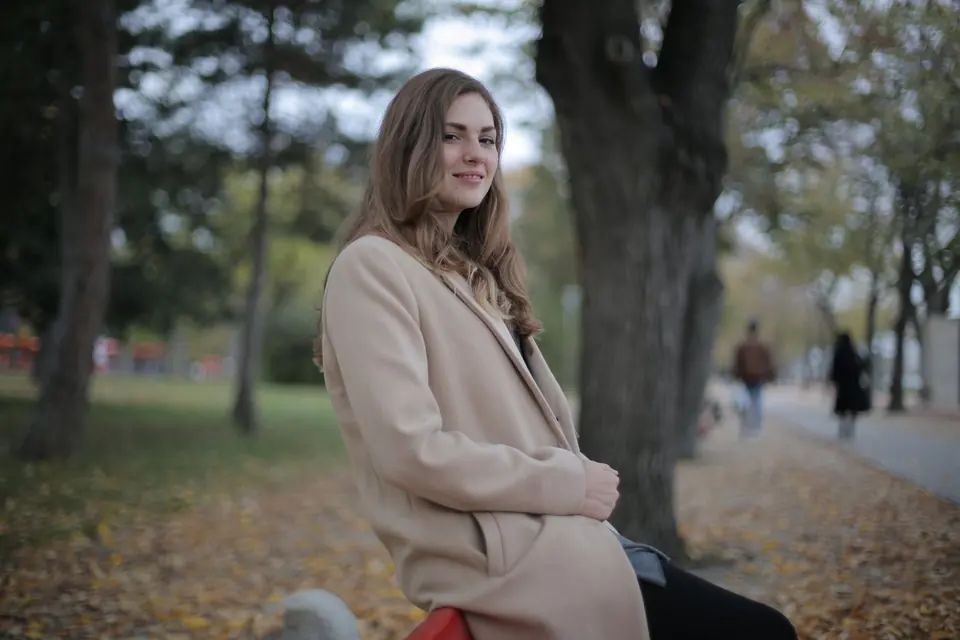 Femke zit op een bankje in het park en lacht