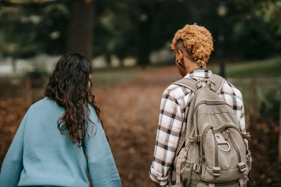 Twee vrouwen wandelen op de rug gezien door een herfstig park