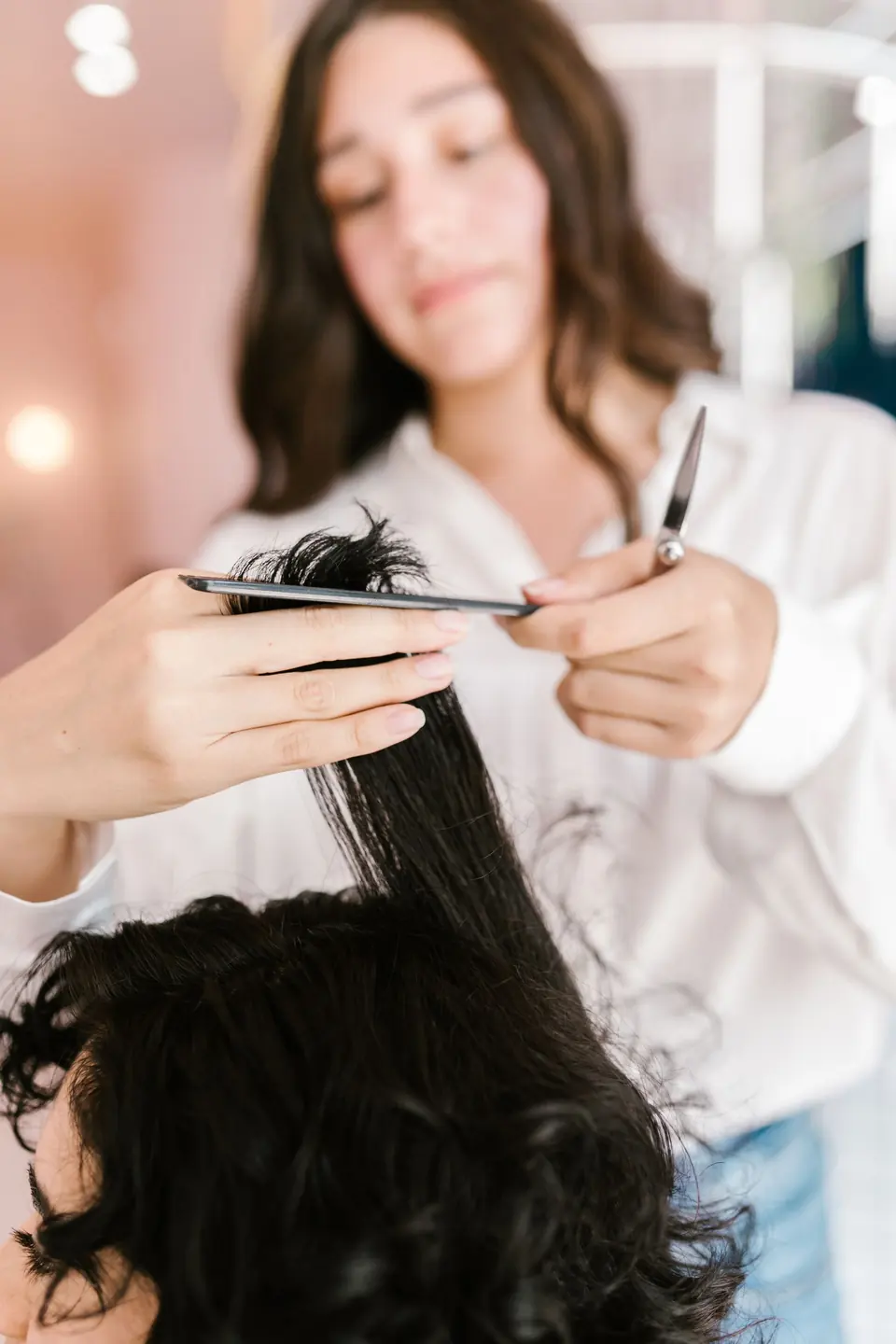 Stylist knipt de punten van lang, donker krullend haar
