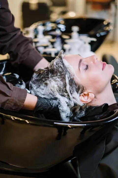 Klant krijgt een hoofdmassage bij de wasbak